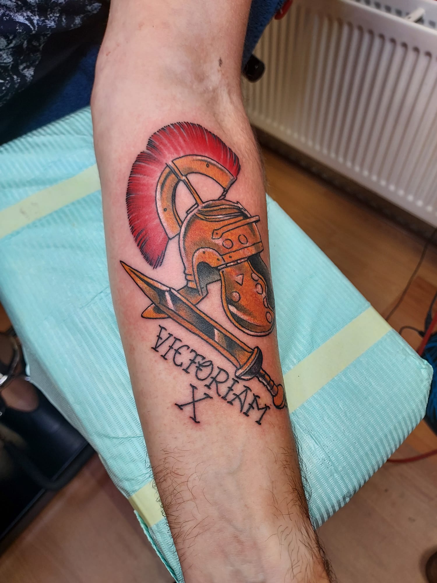 Romeinse helm met zwaard en de tekst Victoriam op een onderarm