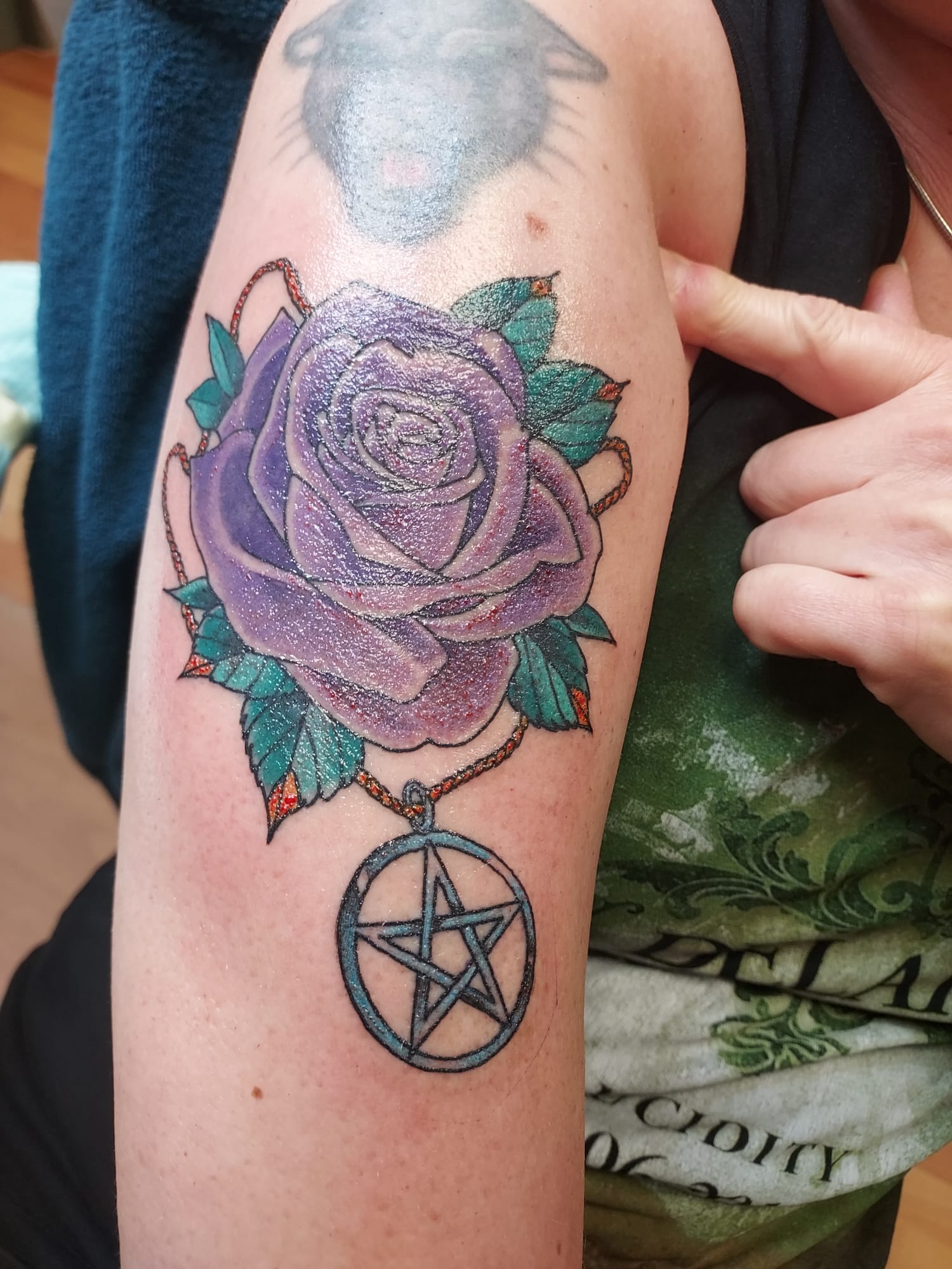 Paarse roos met een pentagram-hanger op een arm