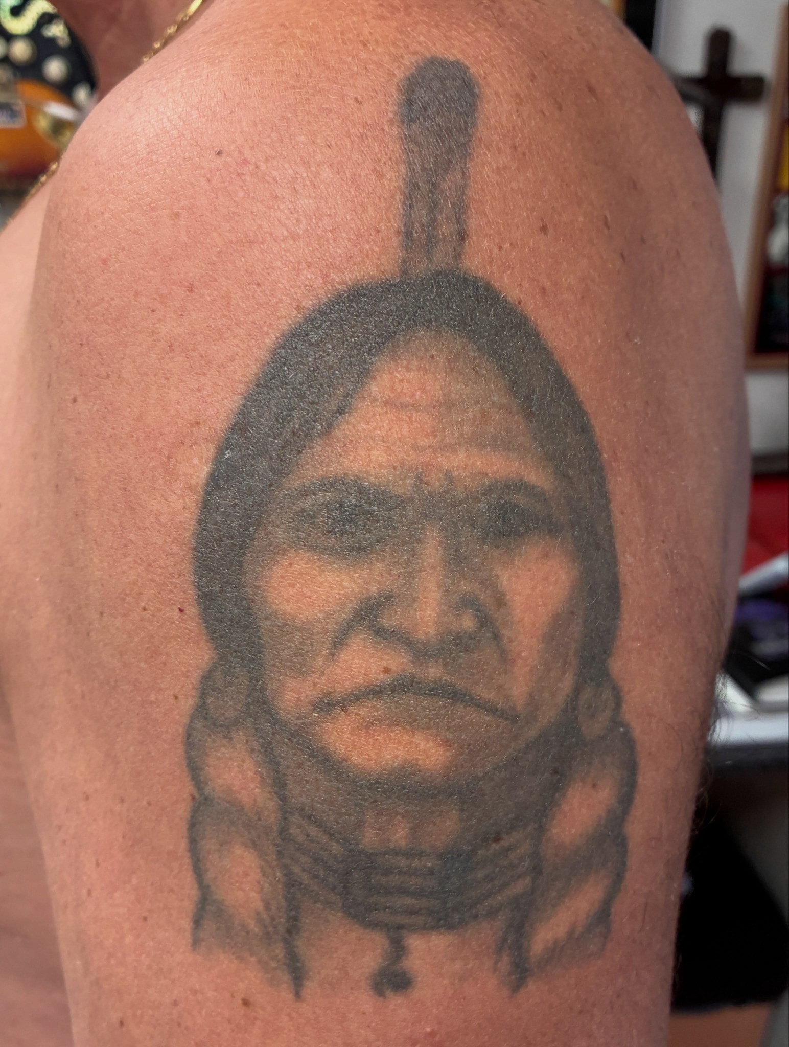 Oude zwart-grijze tattoo van een portret van een indianenhoofdman op een bovenarm