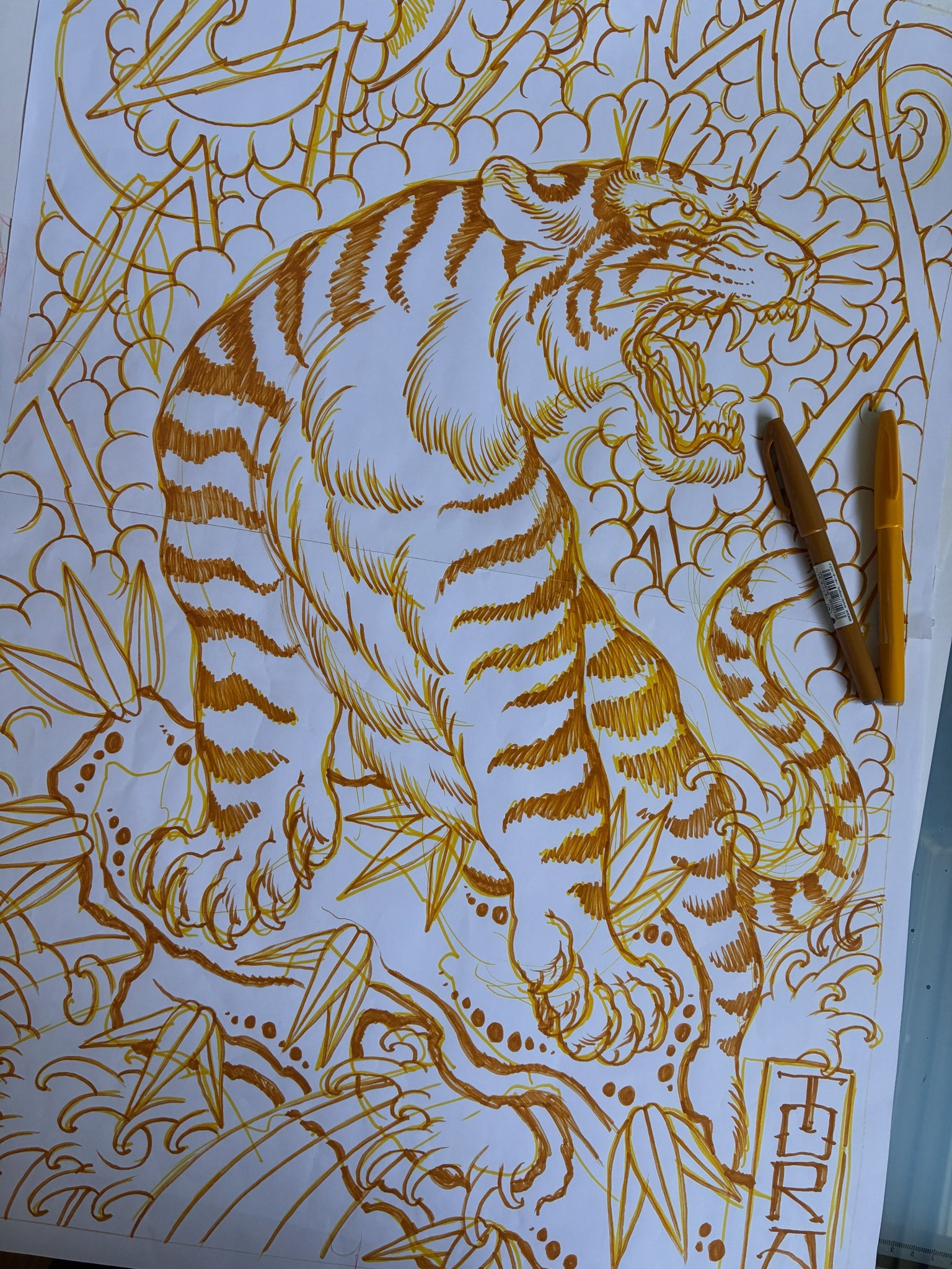 Tekening van een tijger in goudstift op papier, met twee stiften ernaast